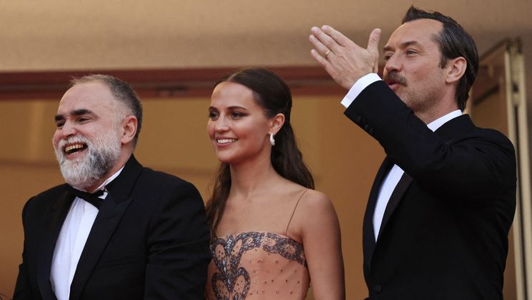 British actor Jude Law (R) waves as he arrives with Swedish actress Alicia Vikander (C) and Brazilian film director Karim Ainouz for the screening of the film "Firebrand" during the 76th edition of the Cannes Film Festival in Cannes, southern France, on May 21, 2023. (Photo by Valery HACHE / AFP) © Valery HACHE / AFP